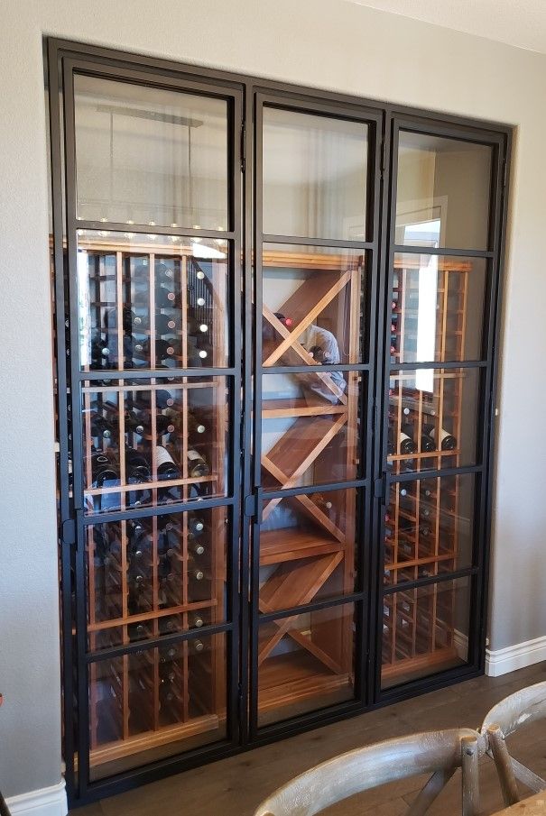 A wine cellar with glass doors and wooden shelves filled with wine bottles.