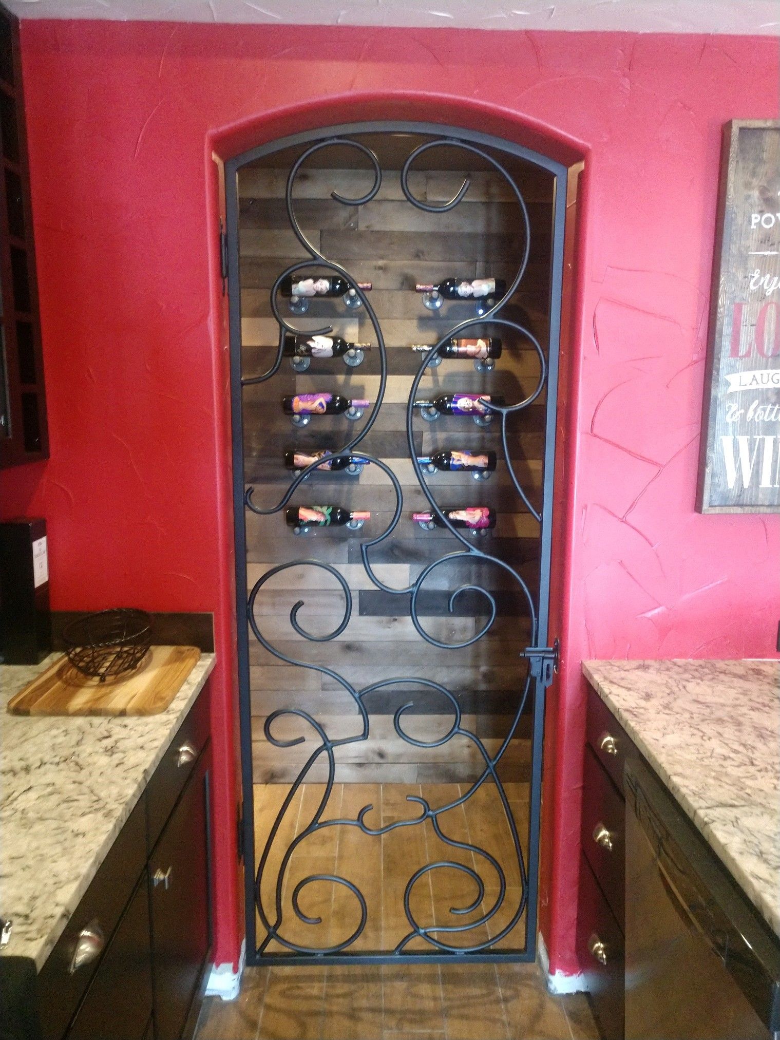 A wine rack is behind a wrought iron gate in a kitchen.