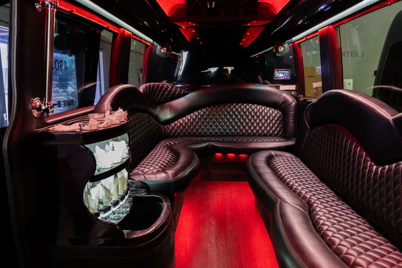 Interior of a limousine with black quilted leather seating and red ambient lighting.