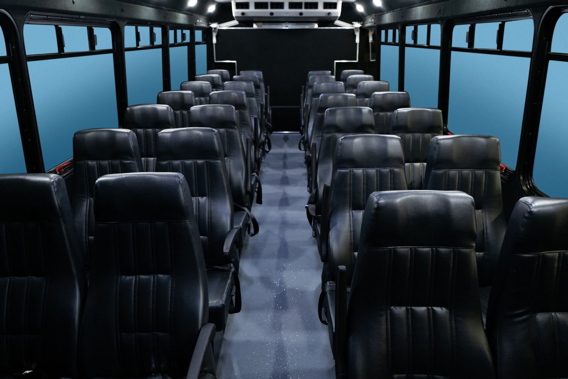 Interior view of an empty black bus with rows of black seats and windows with a blue background.