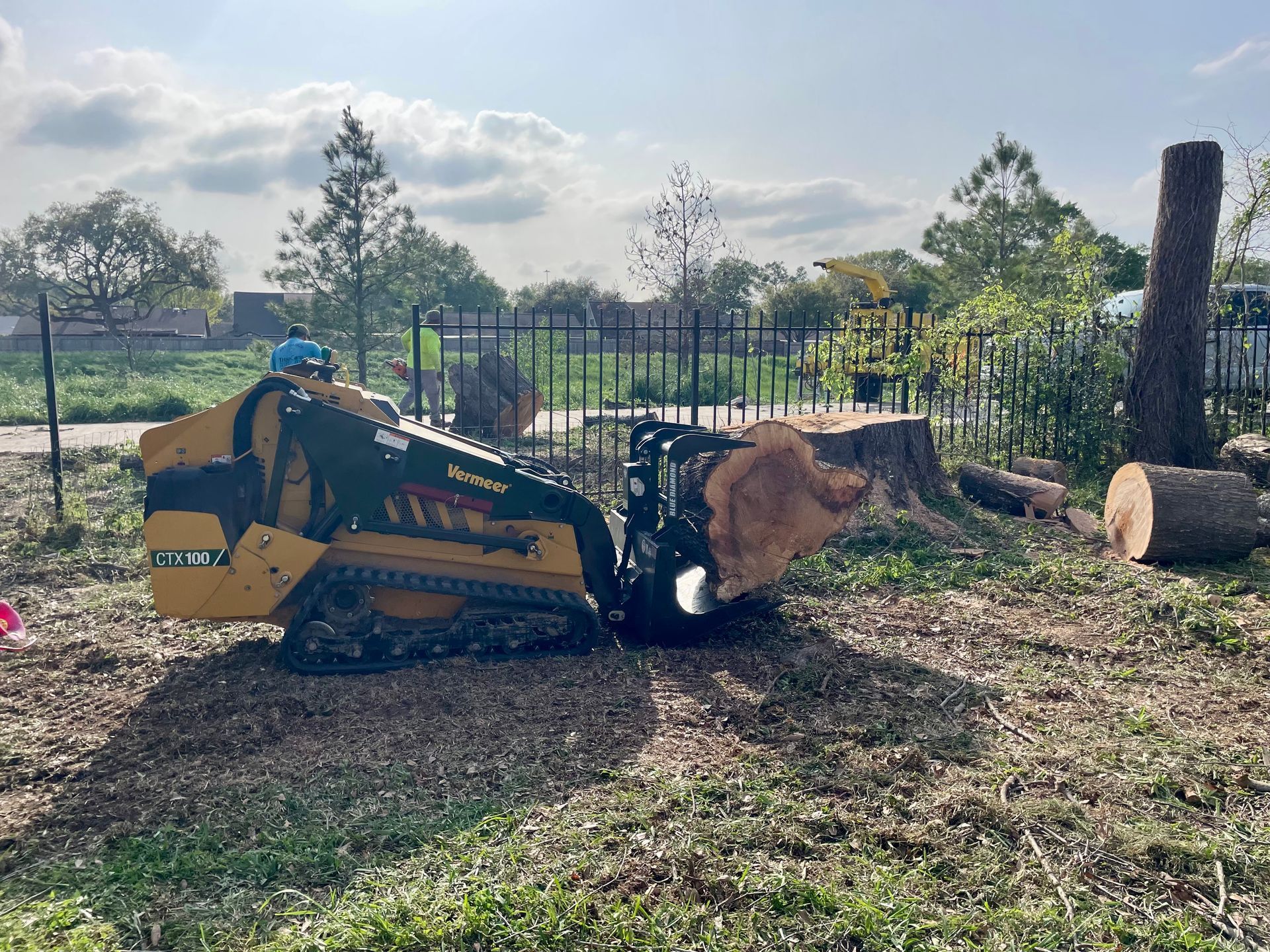 A stump grinder is sitting on top of a tree stump in a field.