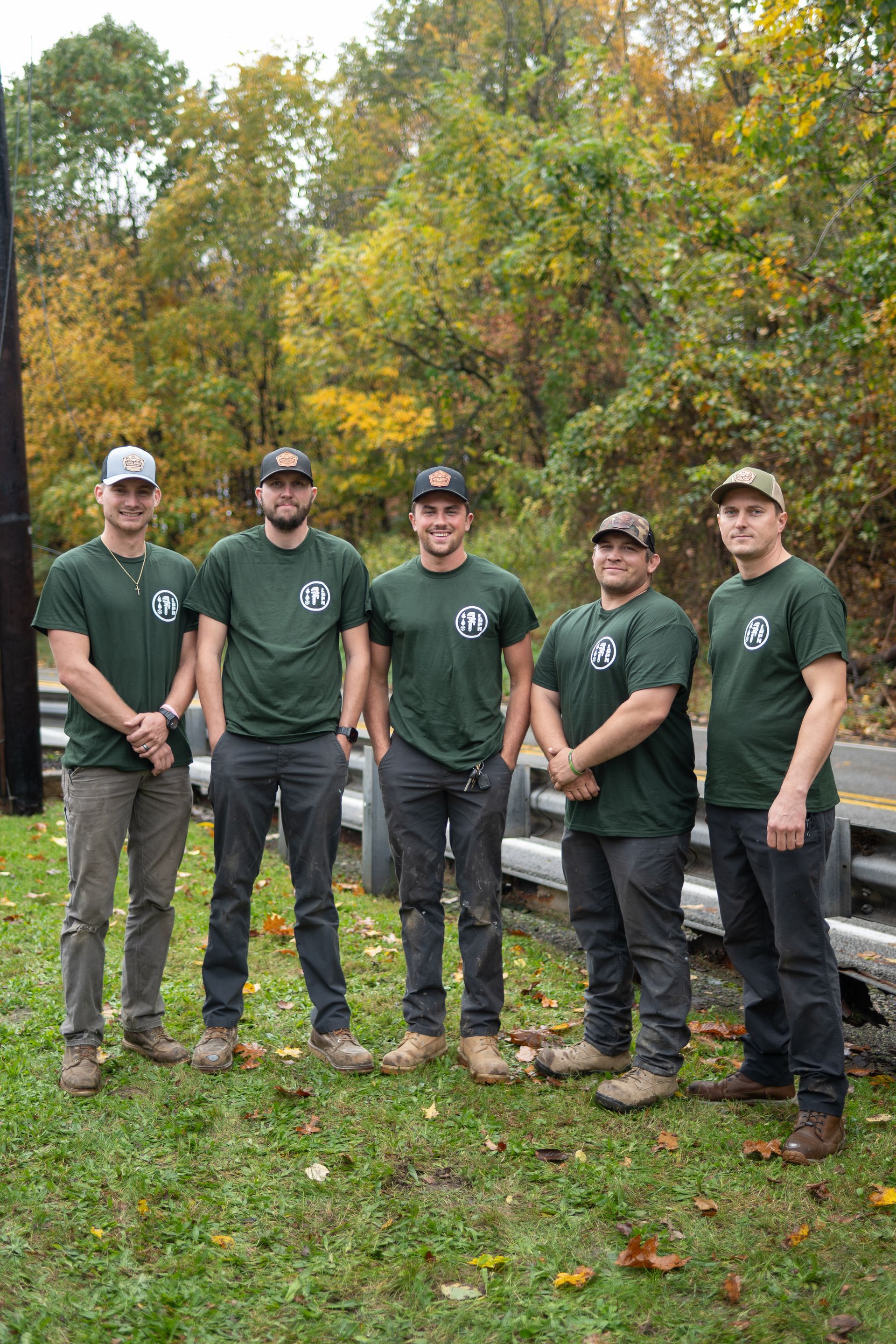 Group of plumbers in uniform posing outside their business.