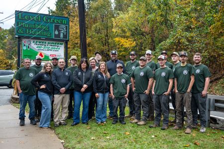 Team of plumbers posing in front of their business sign and truck.