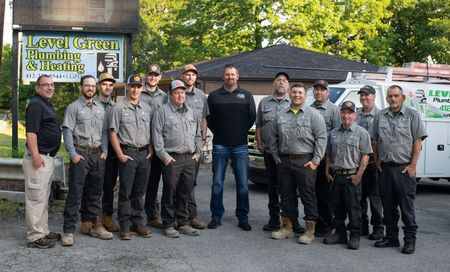 Team of plumbers posing in front of their business sign and truck.