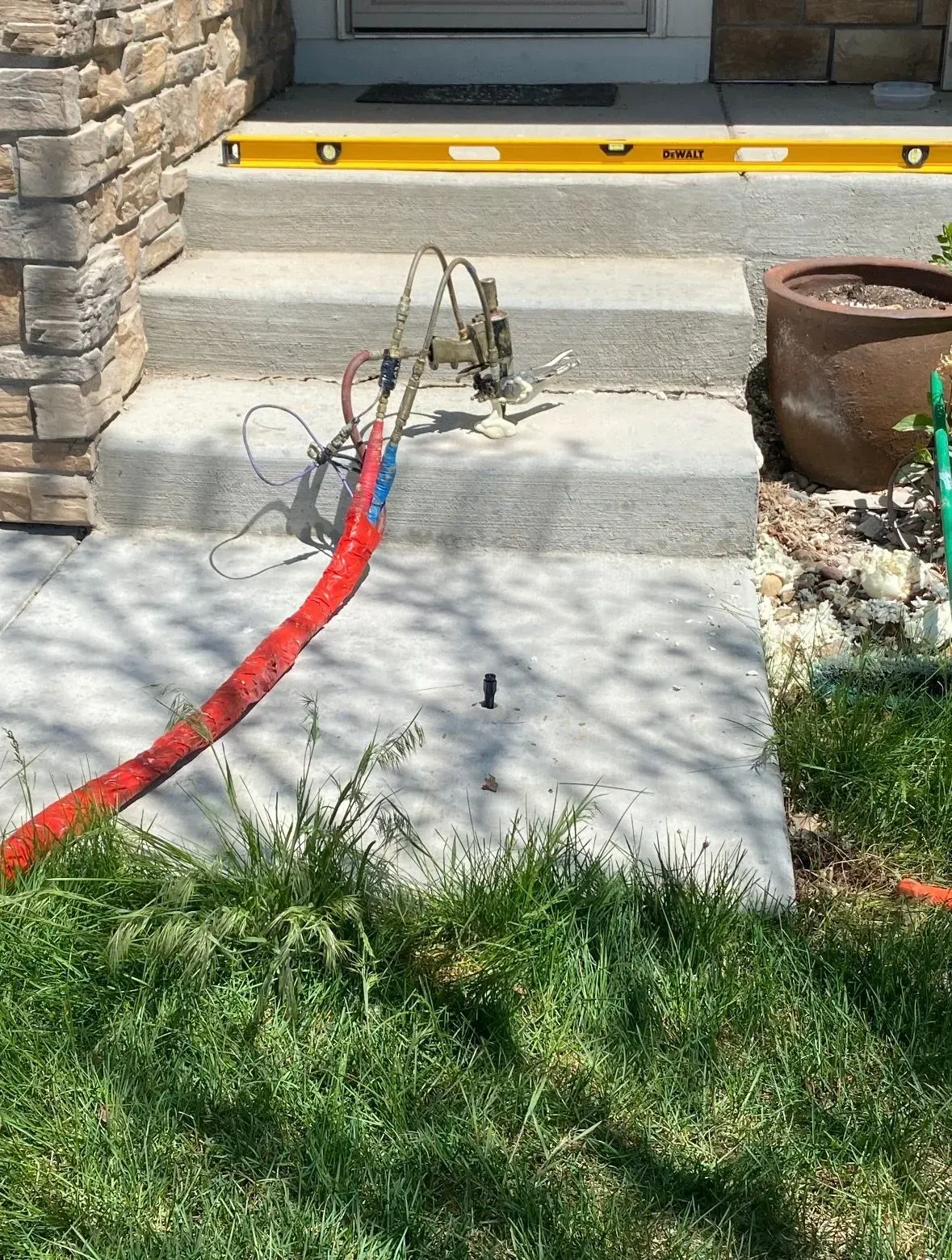 Concrete steps with cables and equipment. A level sits on the top step, near a front door.