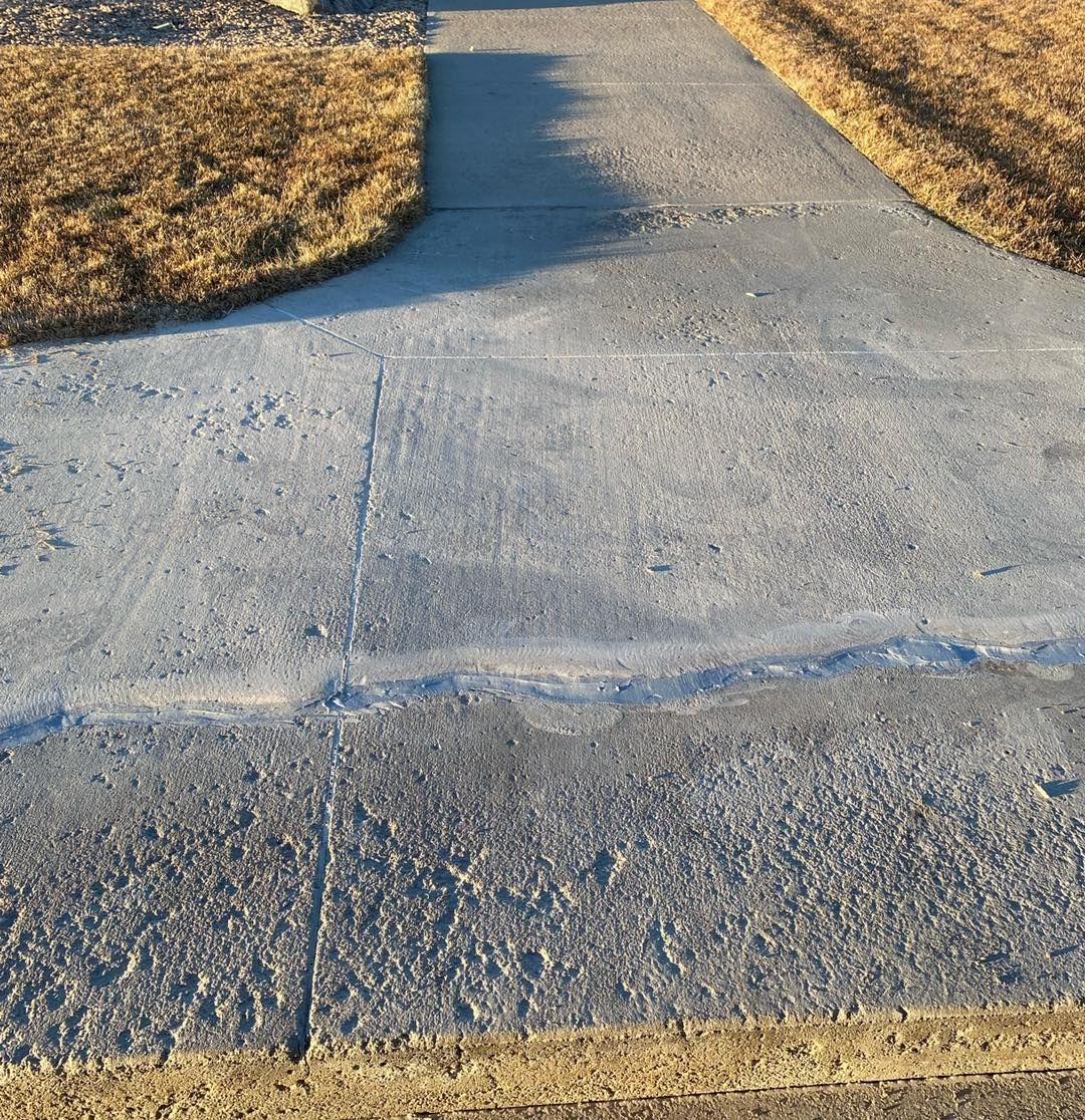 Wet concrete surface with orange marker stakes. A large decorative pot sits on gravel.