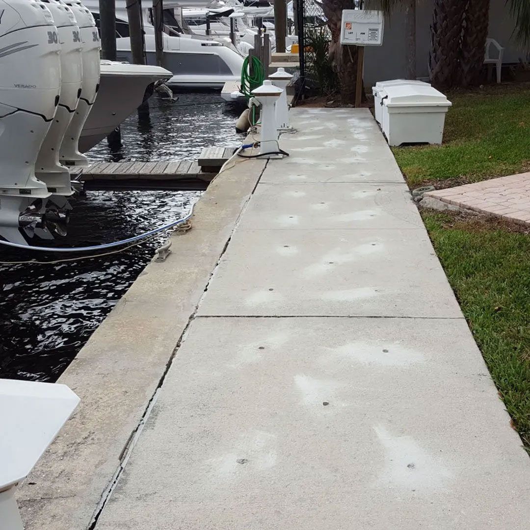 Concrete walkway beside boats docked at a marina.