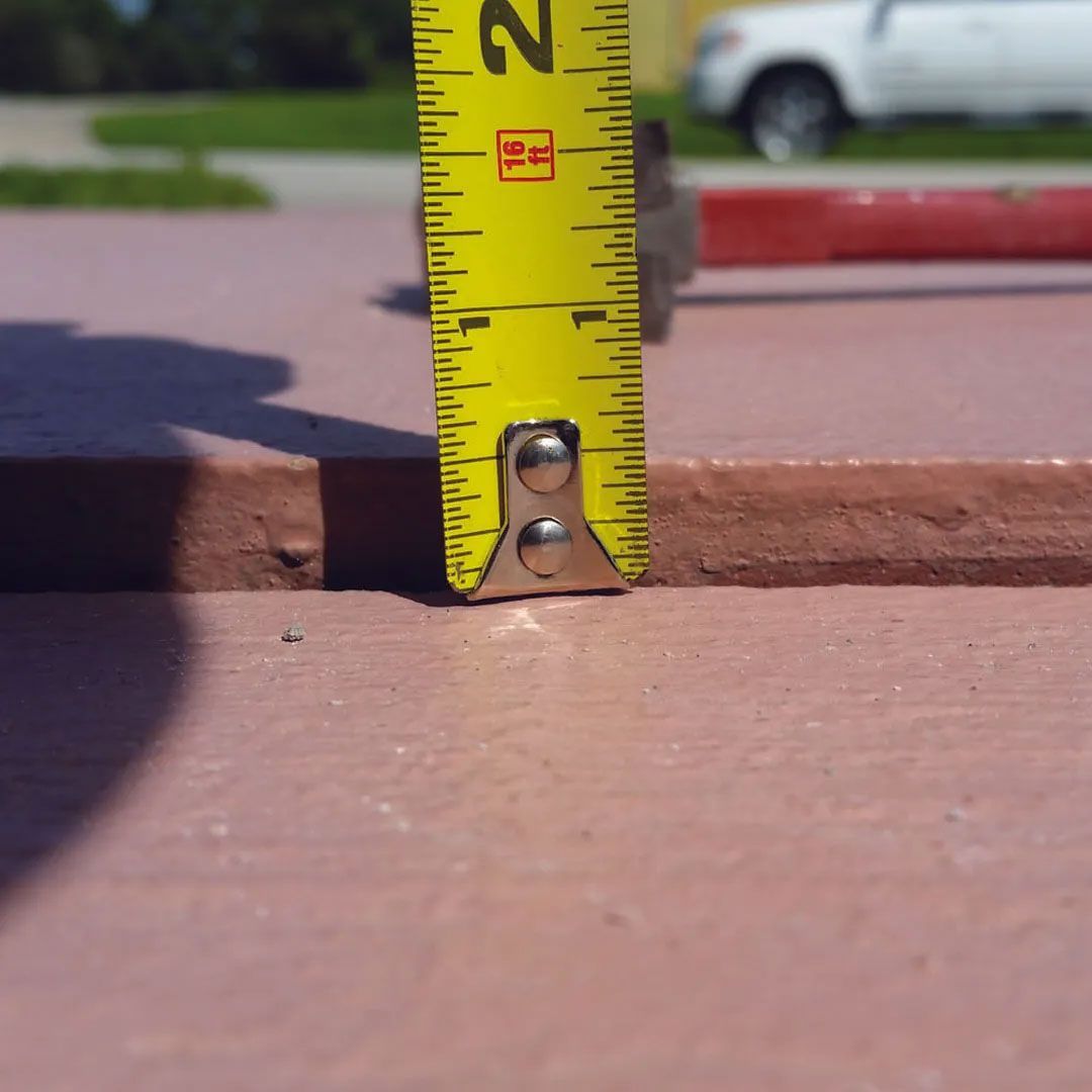 Tape measure showing a measurement of approximately 1 inch on a reddish-brown surface.