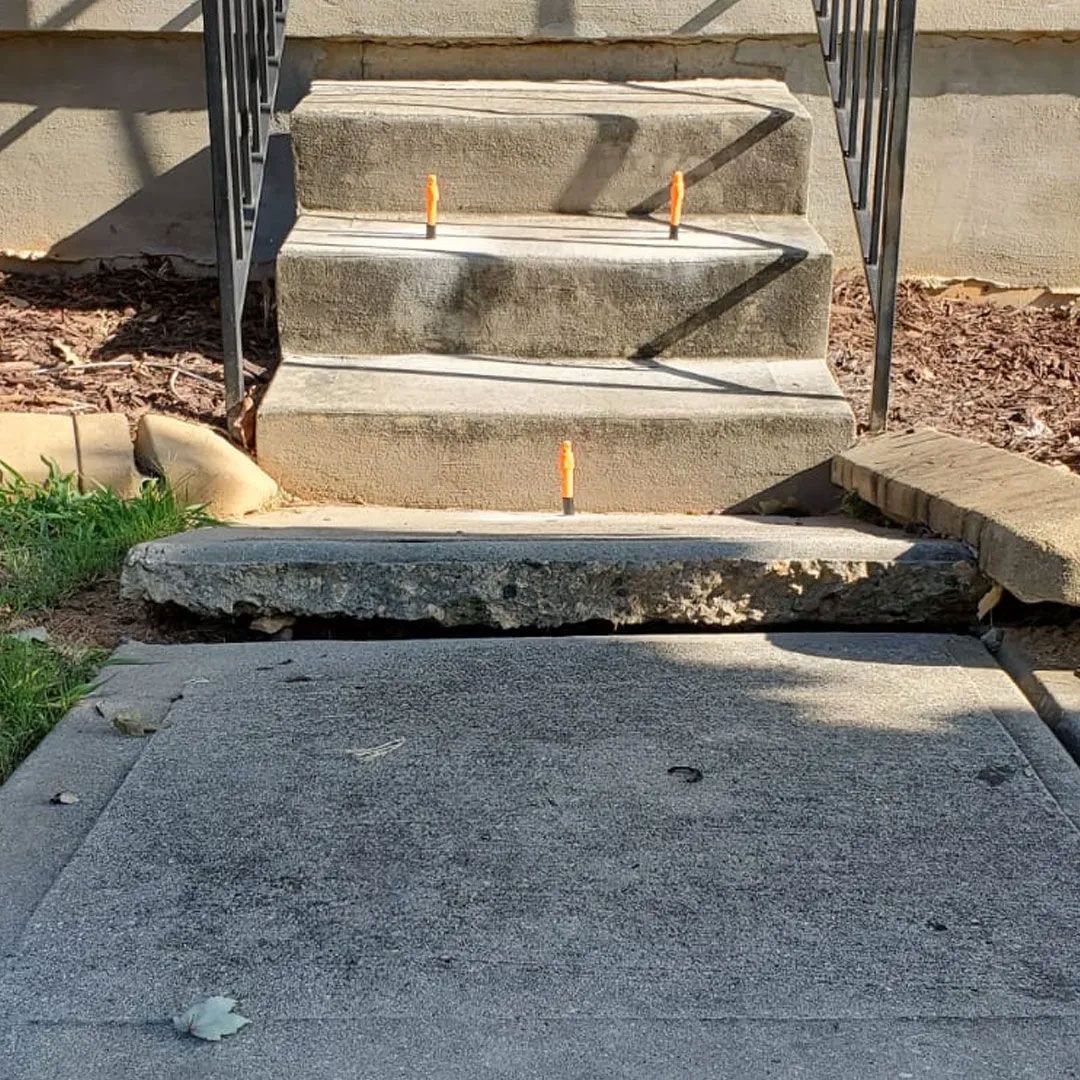 Concrete steps leading up, damaged at the bottom. Yellow pencils mark edges. Railings on either side.