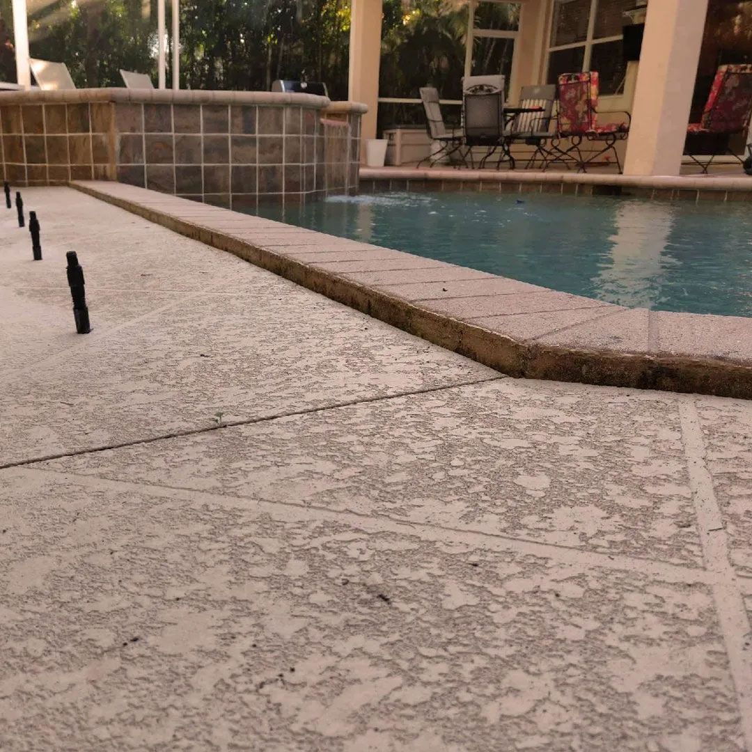 Poolside patio with textured concrete and pool with water feature.