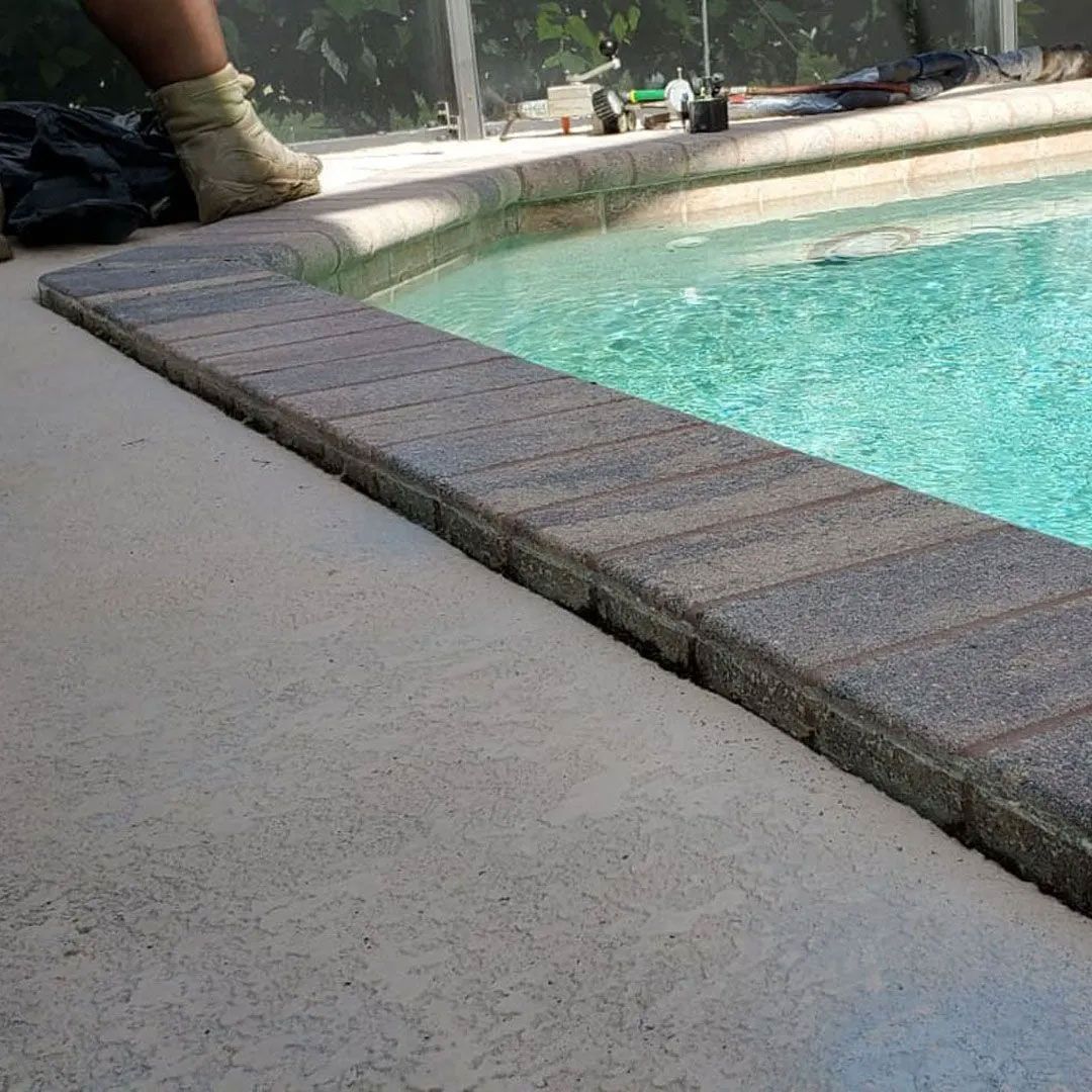 Pool coping with brick pavers bordering pool water.