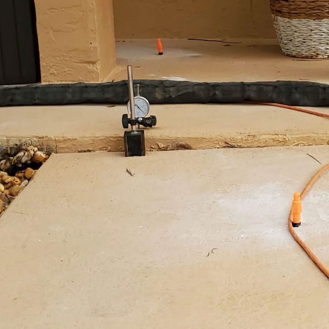 A dial indicator measures the level of a concrete surface.