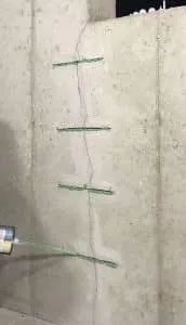 Concrete wall with a vertical crack, marked by green indicators.