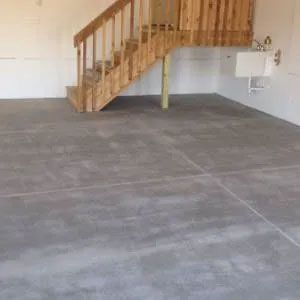 Concrete floor in a mostly empty room with wooden stairs leading up and a utility sink.