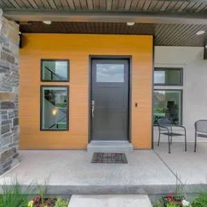 Modern home entrance: brown door, windows, orange panel, gray stone, concrete porch.