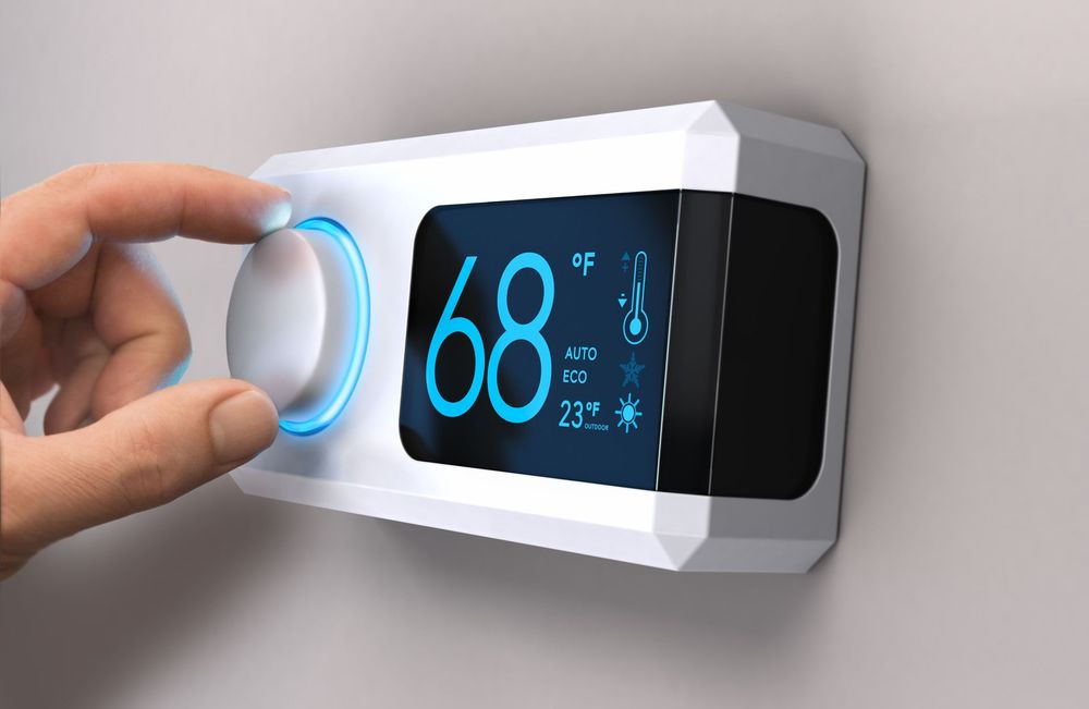 A person is adjusting a thermostat on a wall.