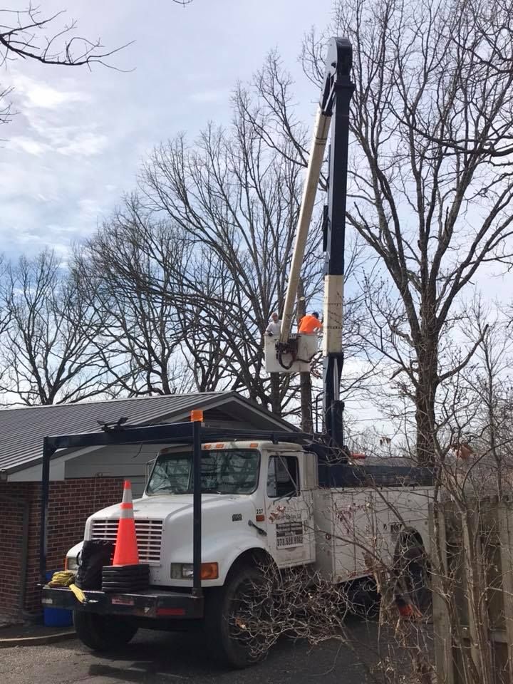 Utility truck with extended lift arm near a building, worker in bucket.