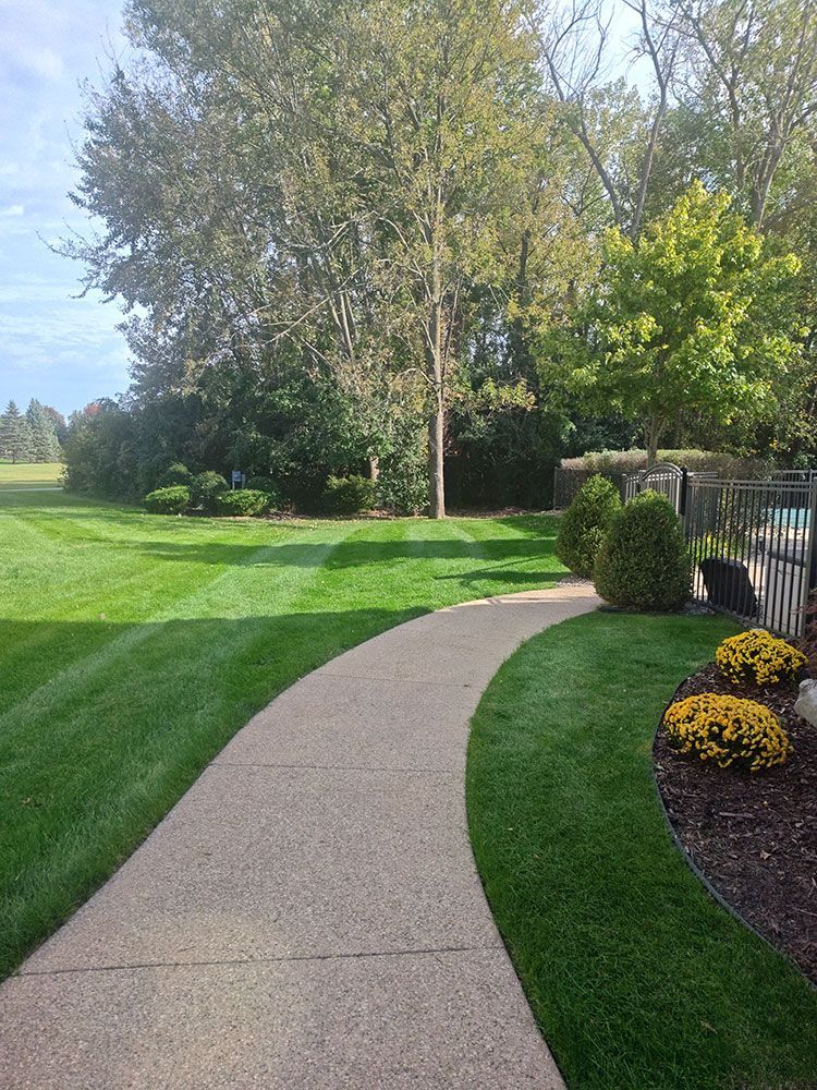 A concrete walkway leading to a lush green lawn.