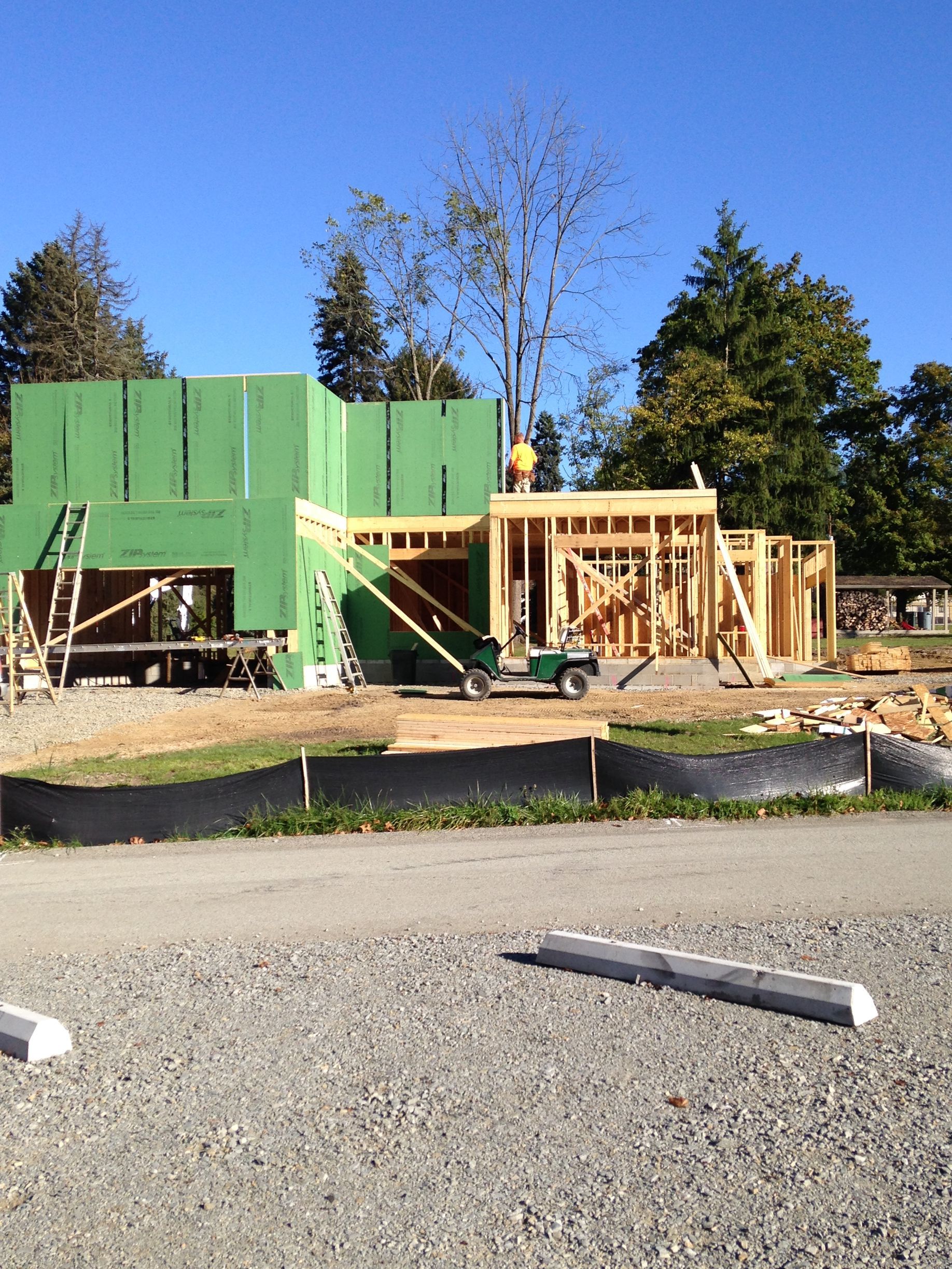Construction site with green and wood house framing under a clear blue sky