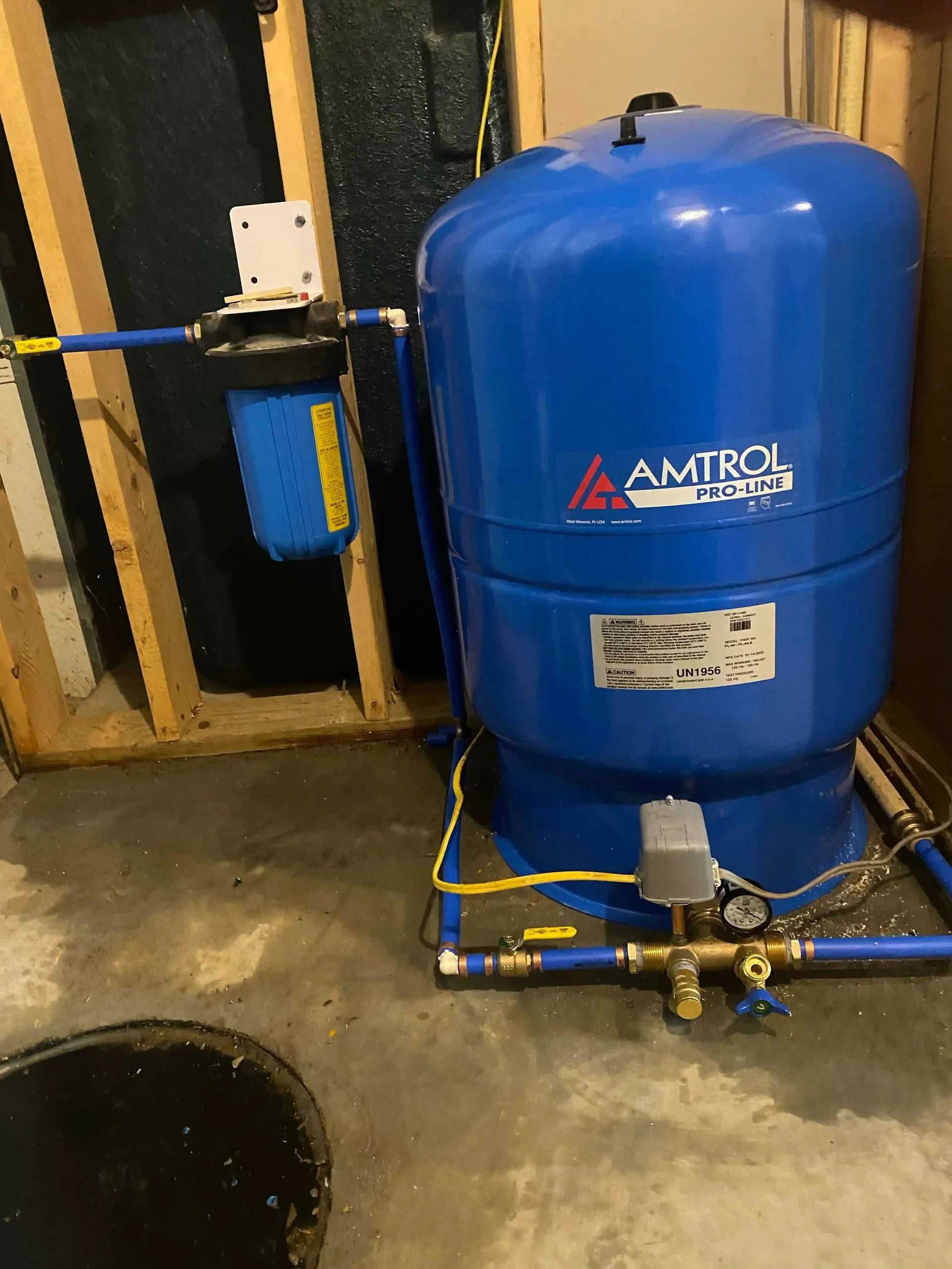 Blue air compressor tank with gauges and attached filters in an industrial basement setting