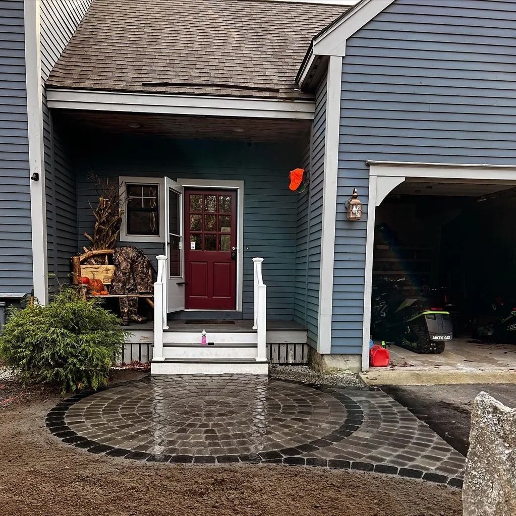Blue house with red door and brick pathway. Open garage.