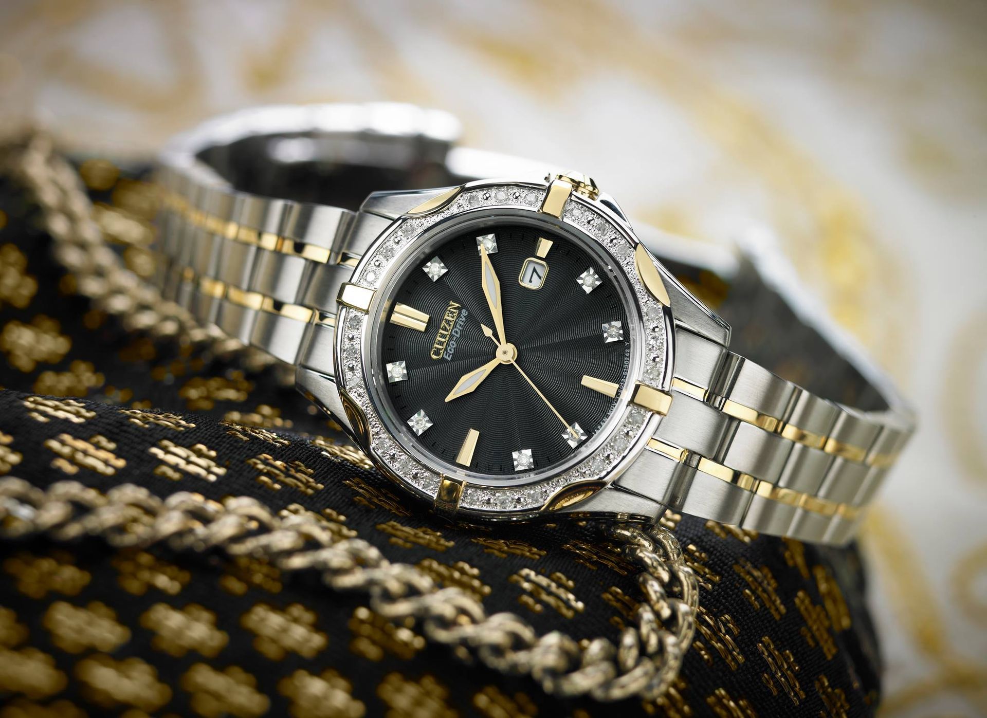 A silver and gold watch with a black face and diamonds