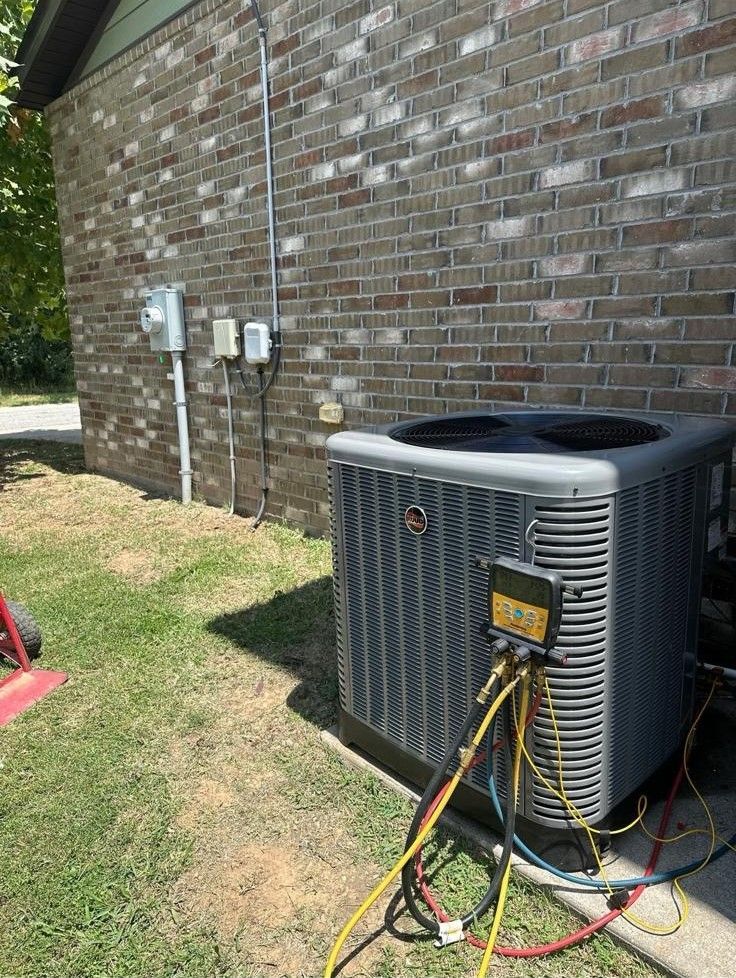An air conditioner is being installed on the side of a brick house.