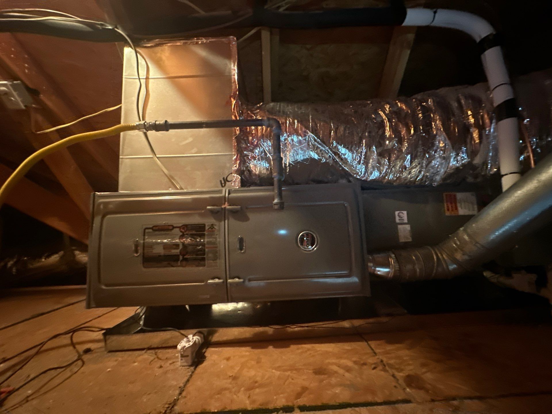 An air conditioner is sitting in the attic of a house.