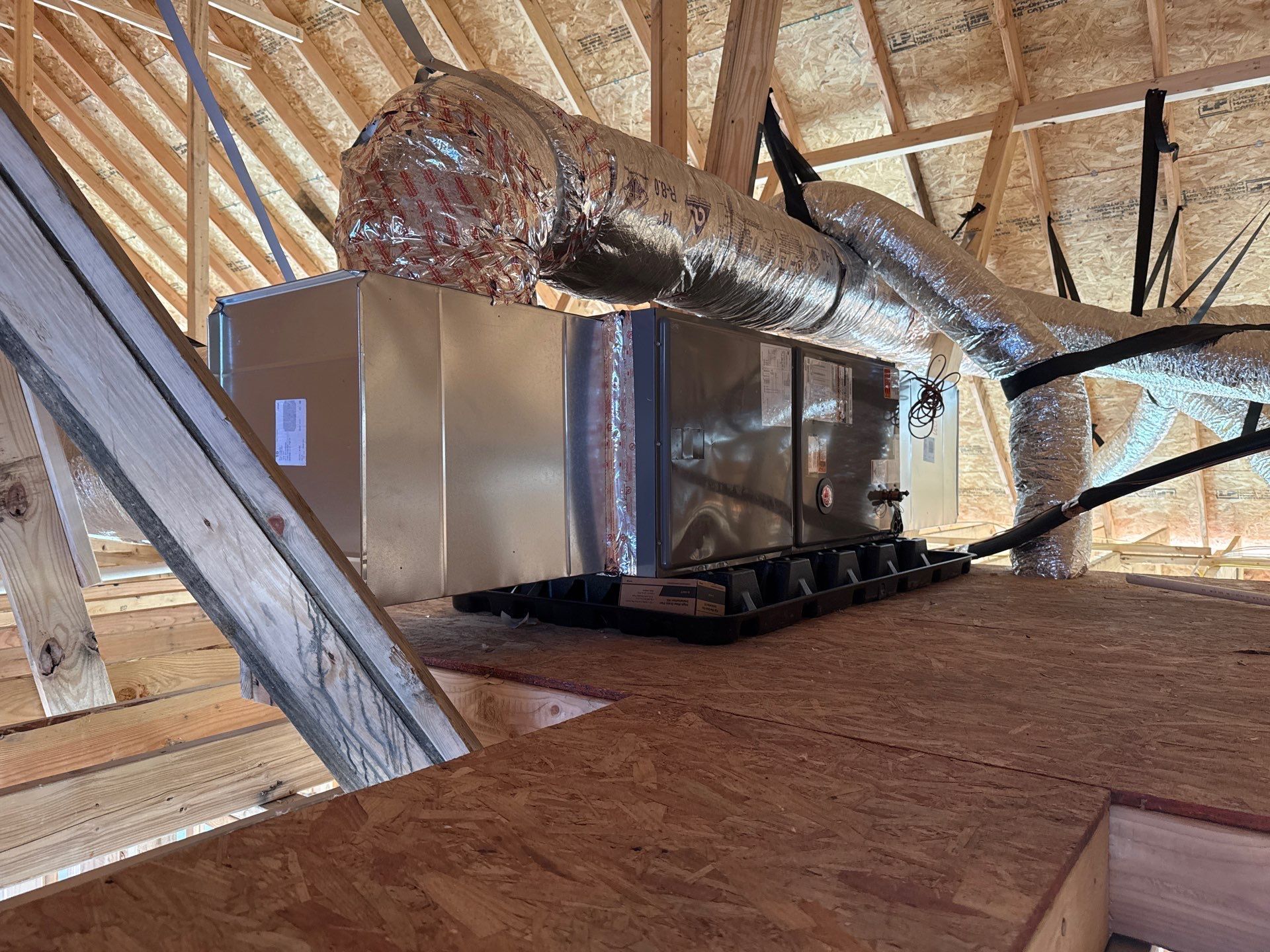 A ventilation system is being installed in the attic of a house under construction.