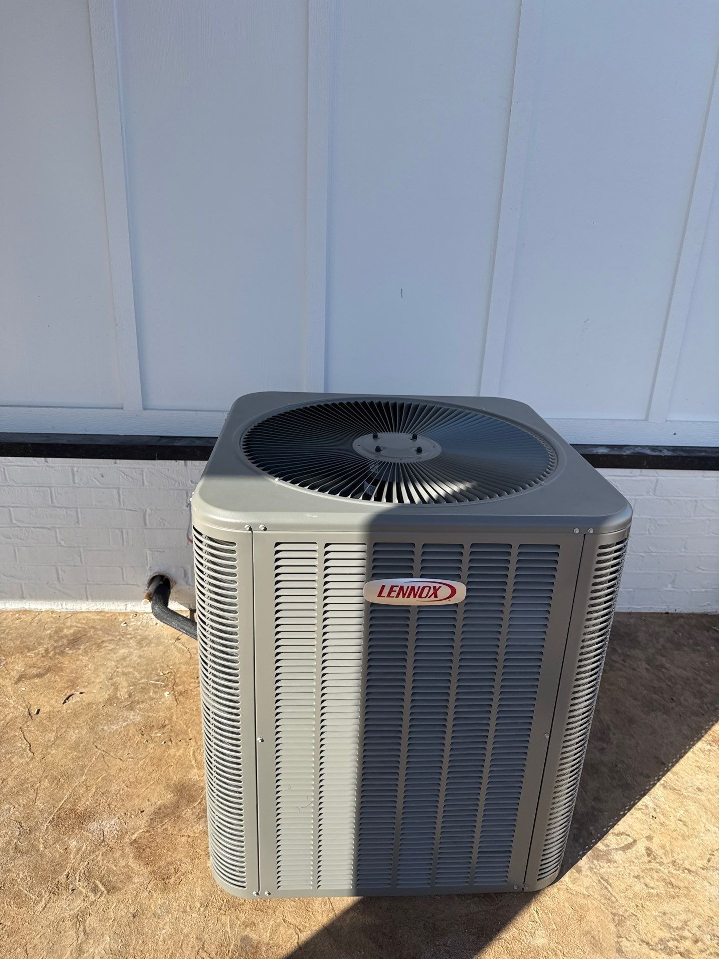 A large air conditioner is sitting on the ground in front of a white wall.