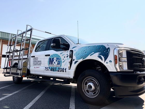White utility truck with company logo parked outdoors on a sunny street, side view