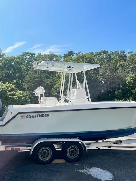 White Contender boat on a trailer, blue trim, white canopy, sunny day.