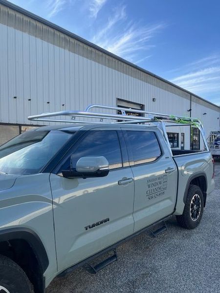 Gray truck with roof rack parked in front of a white building.