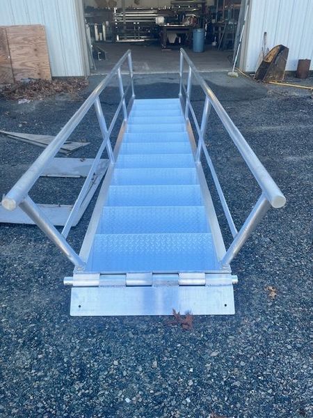 Aluminum stairway with handrails, leading into a building.