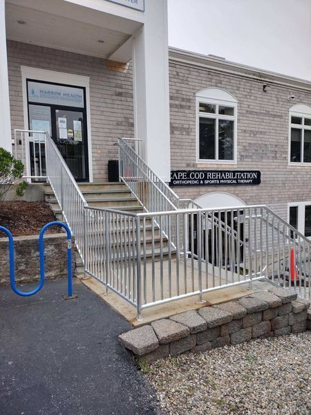 Exterior of a building with a stairwell and ramp to the entrance; Cape Cod Rehabilitation sign visible.