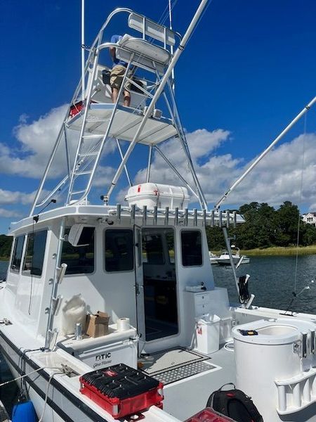 White fishing boat with a tall tower under a blue sky.