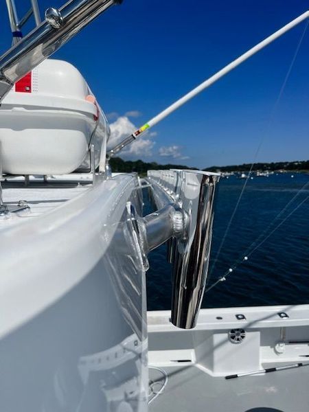 Fishing rod holder on a white boat, water and blue sky background.