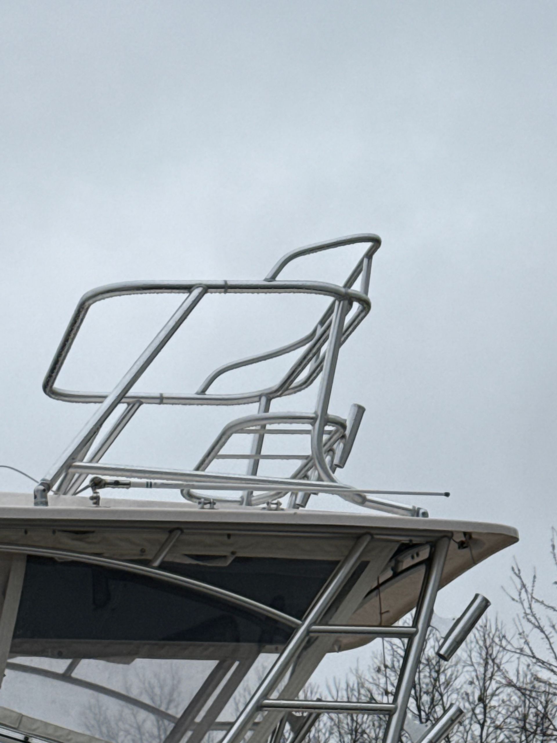 Boat's elevated helm station with silver metal framing. Cloudy sky in the background.