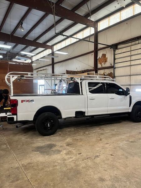 White pickup truck with a ladder rack in a warehouse setting.