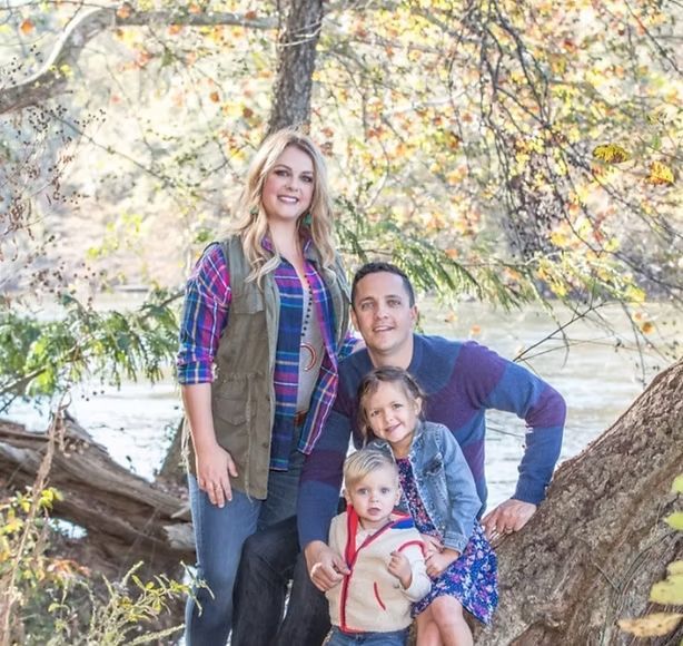 A family is posing for a picture while sitting on a tree branch.
