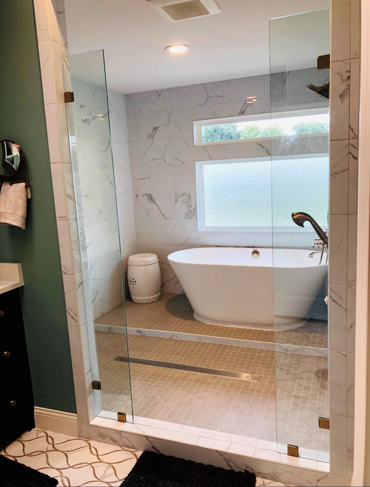 Modern bathroom with glass shower, freestanding tub, and frosted window.