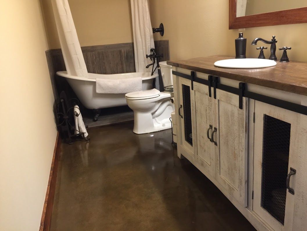 Bathroom with clawfoot tub, toilet, and vanity with sink and mirror in a beige room