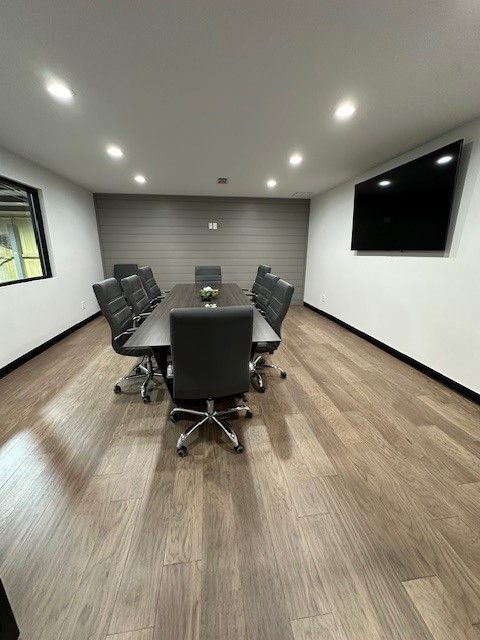 A conference room with a long table, chairs, and a flat screen TV