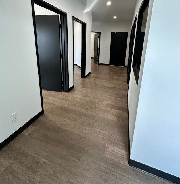 A hallway with wooden floors and black doors