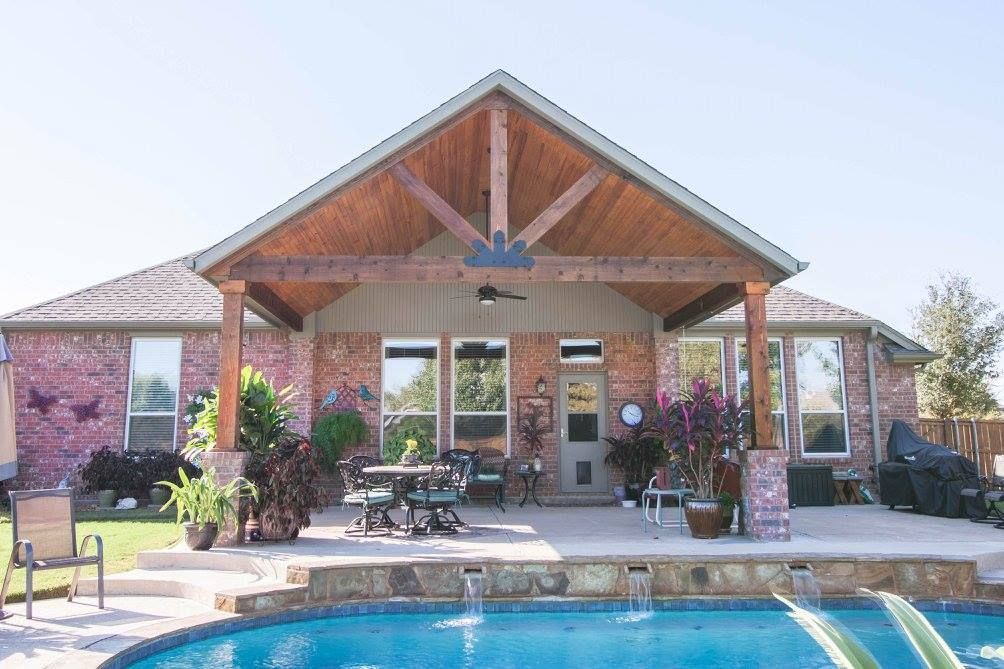 A house with a covered patio and a pool in front of it