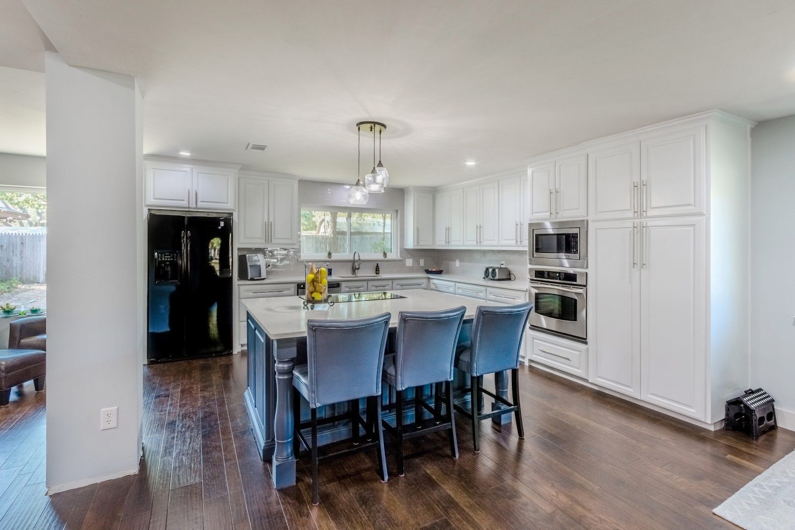 A kitchen with white cabinets, stainless steel appliances, and a large island