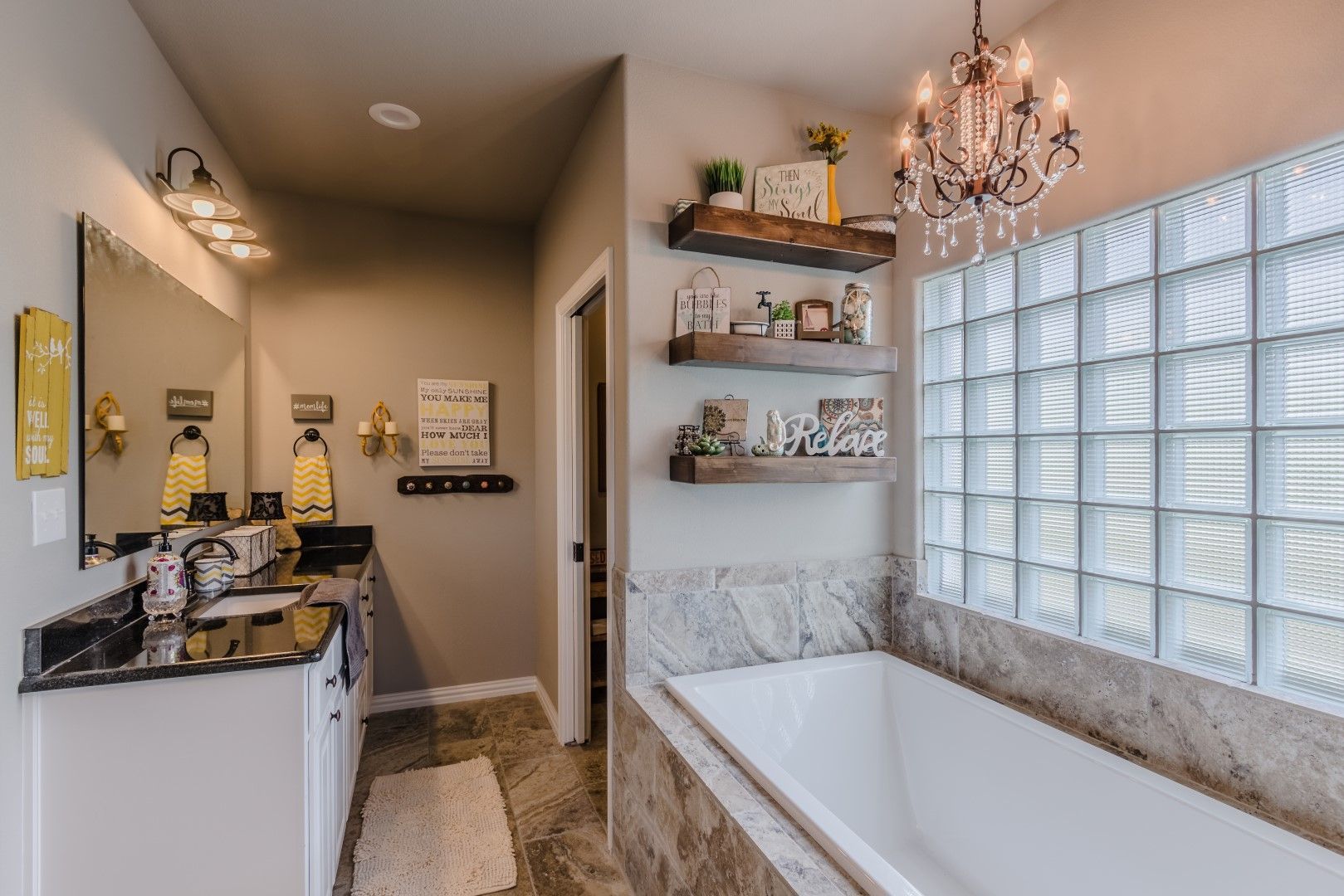 A bathroom with a tub, sink, mirror and chandelier