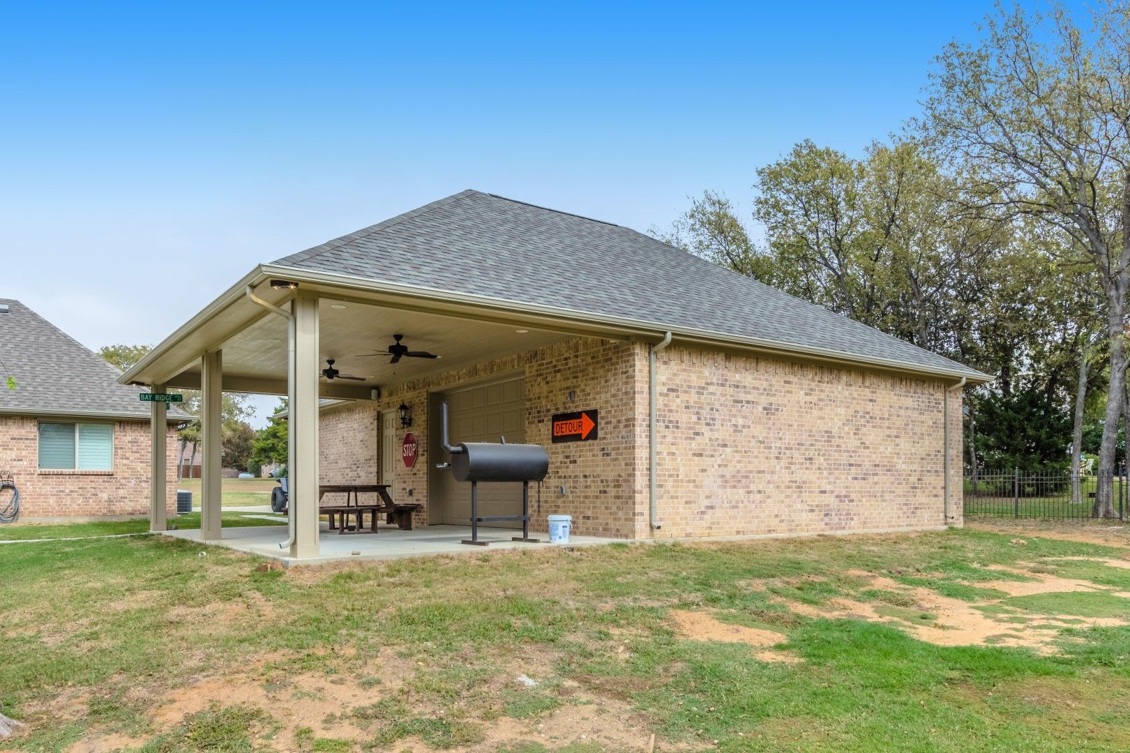 a brick garage with a covered porch and a grill