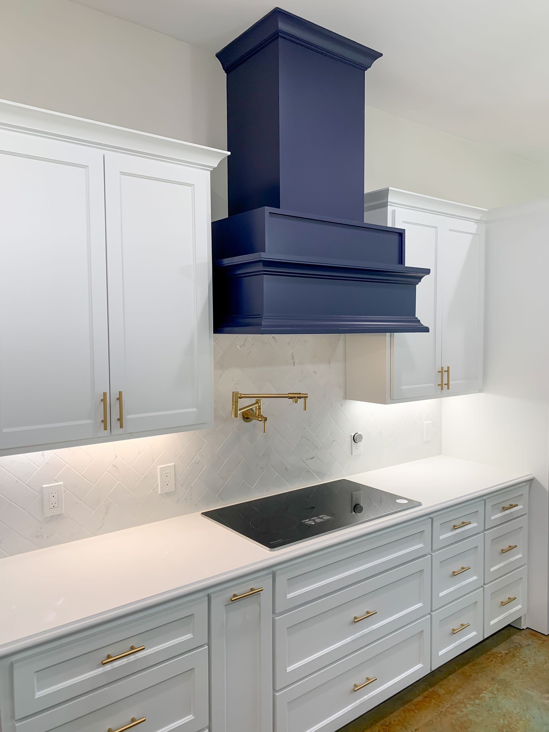 A kitchen with white cabinets and a blue hood above the stove