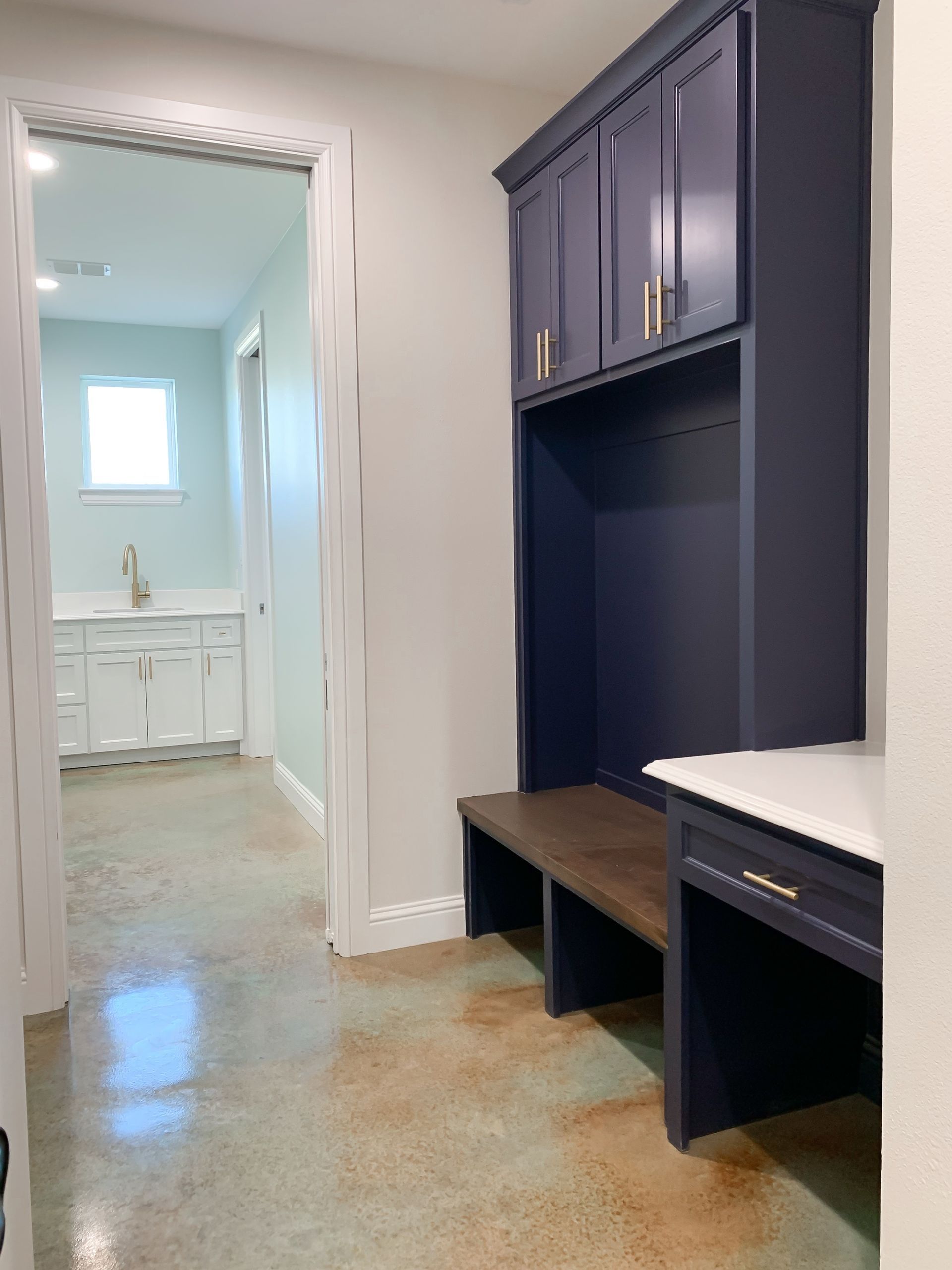 A hallway with blue cabinets and a bench leading to a bathroom